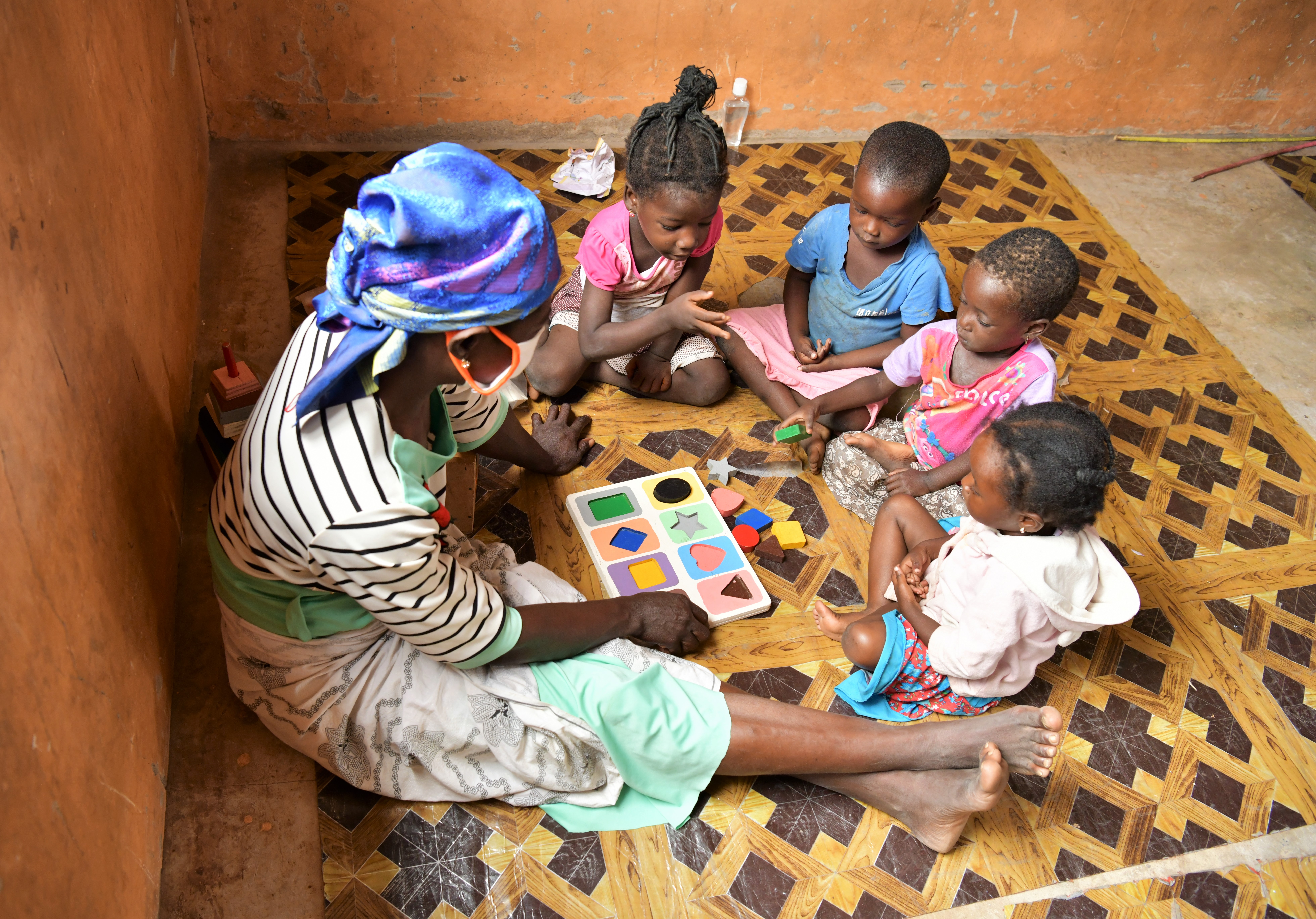 A teacher in reading to students on a classroom floor in Ghana