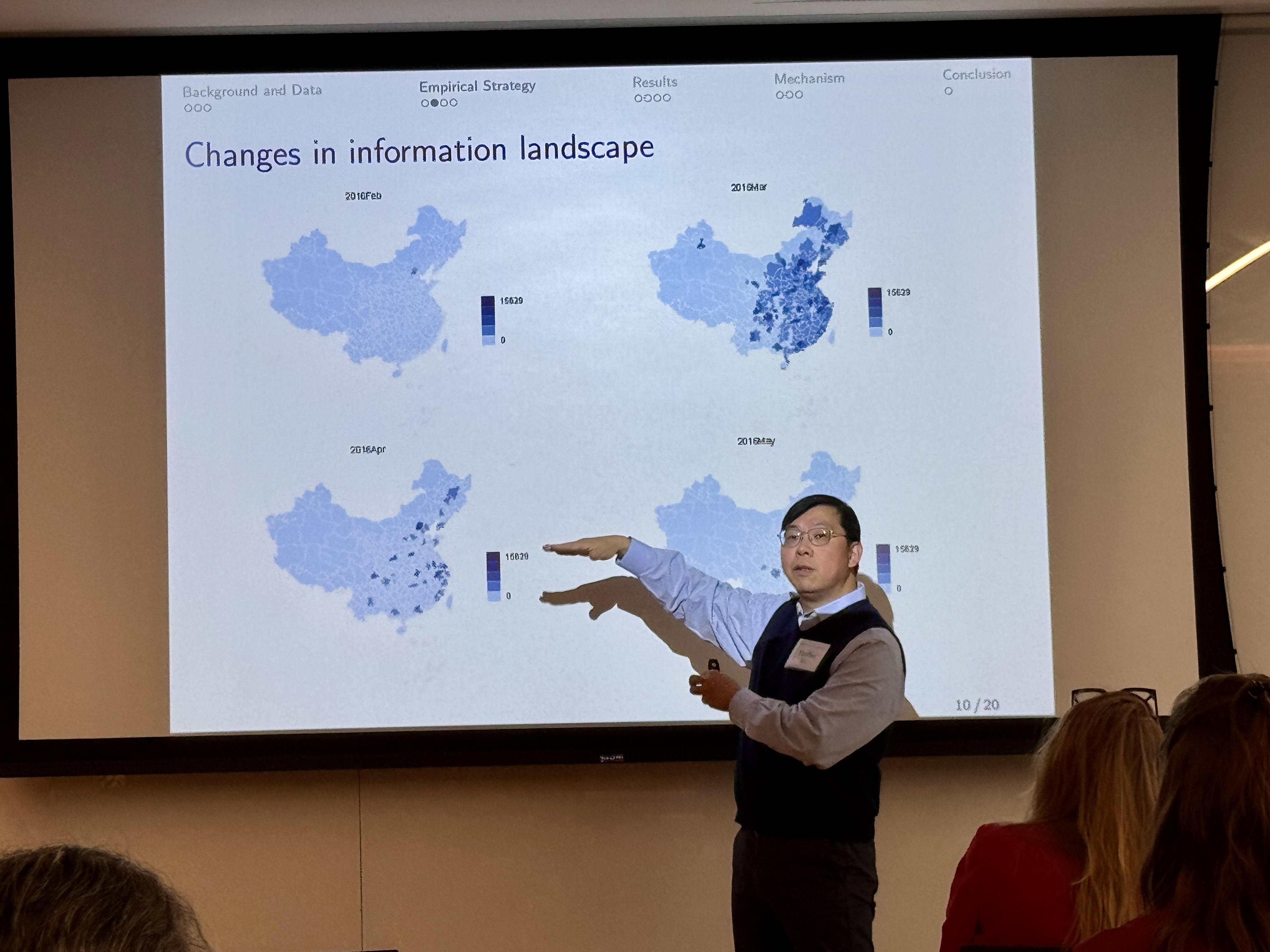 A man in a sweater presents at the front of a classroom