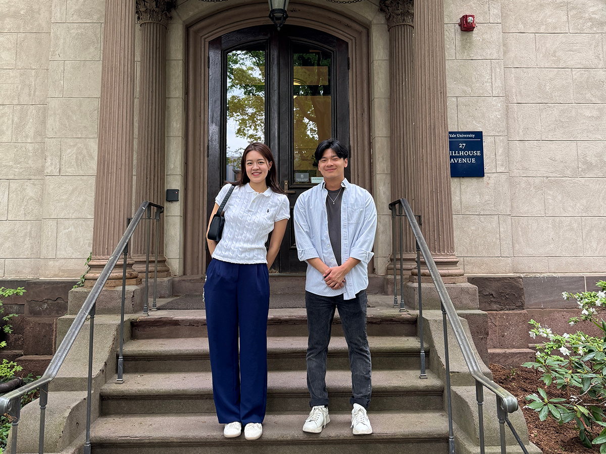 Two student pose at the steps of an academic building