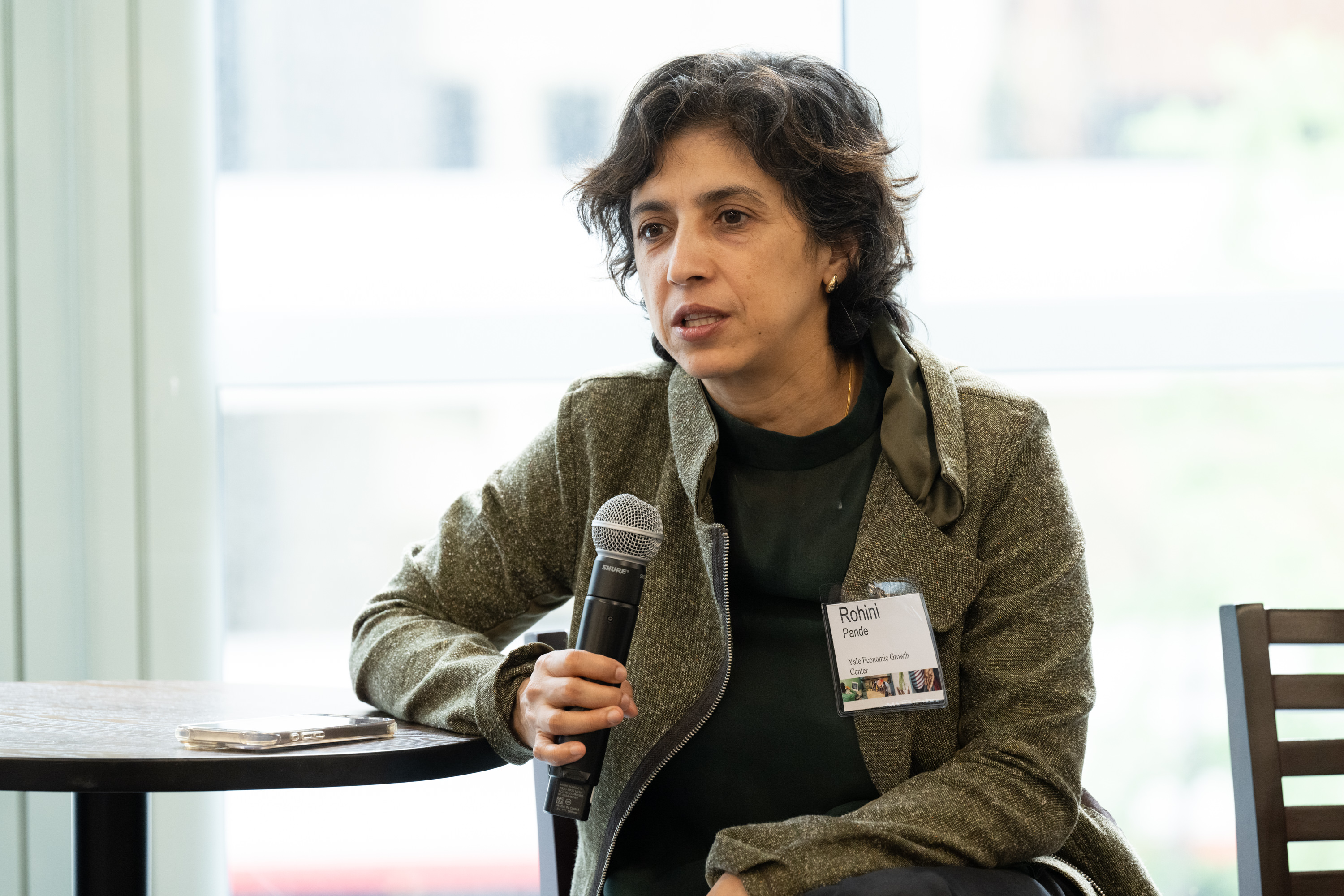A woman in a dark jacket speaks to an audience