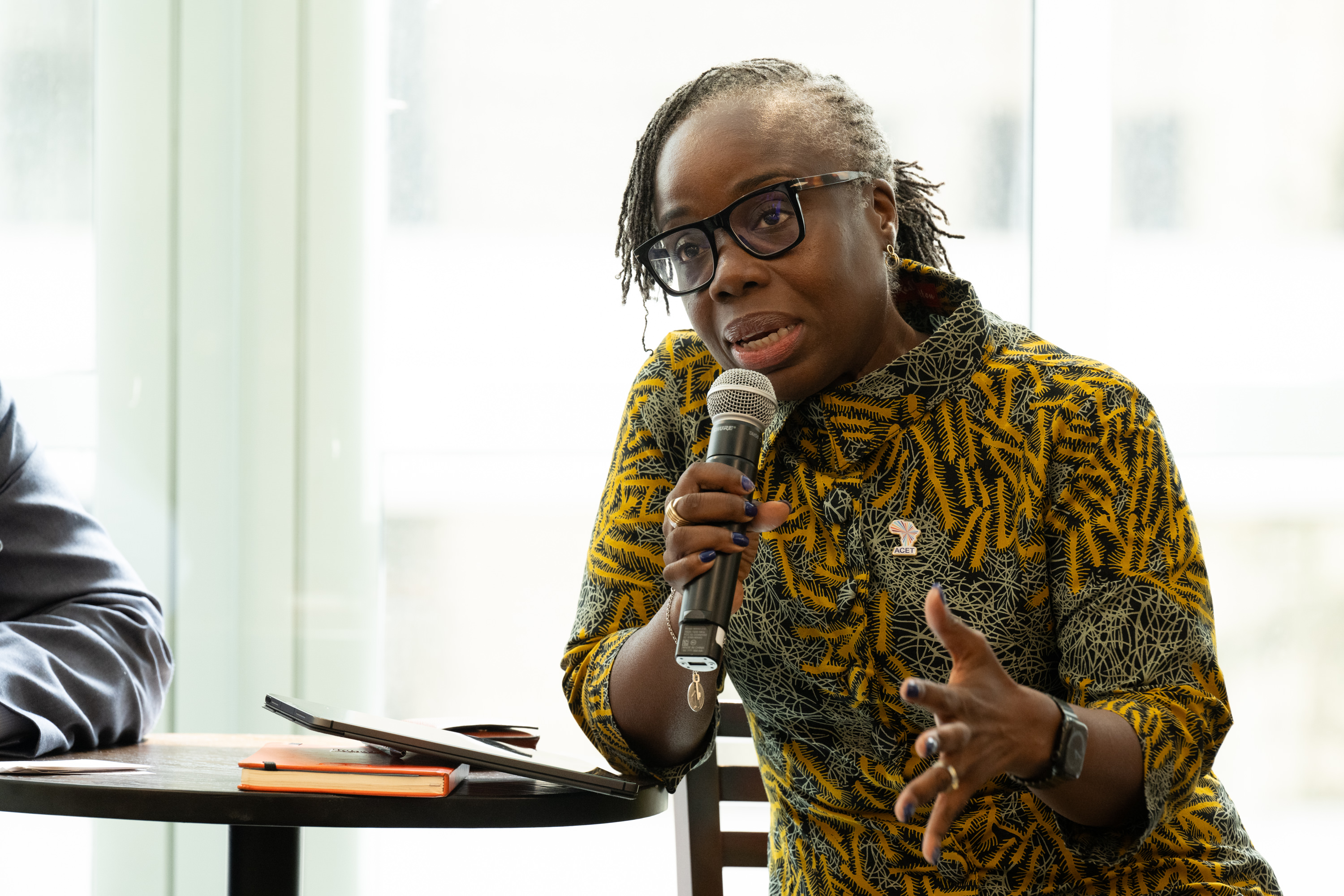 A woman in a patterned dress responds to an audience question during a discussion panel.
