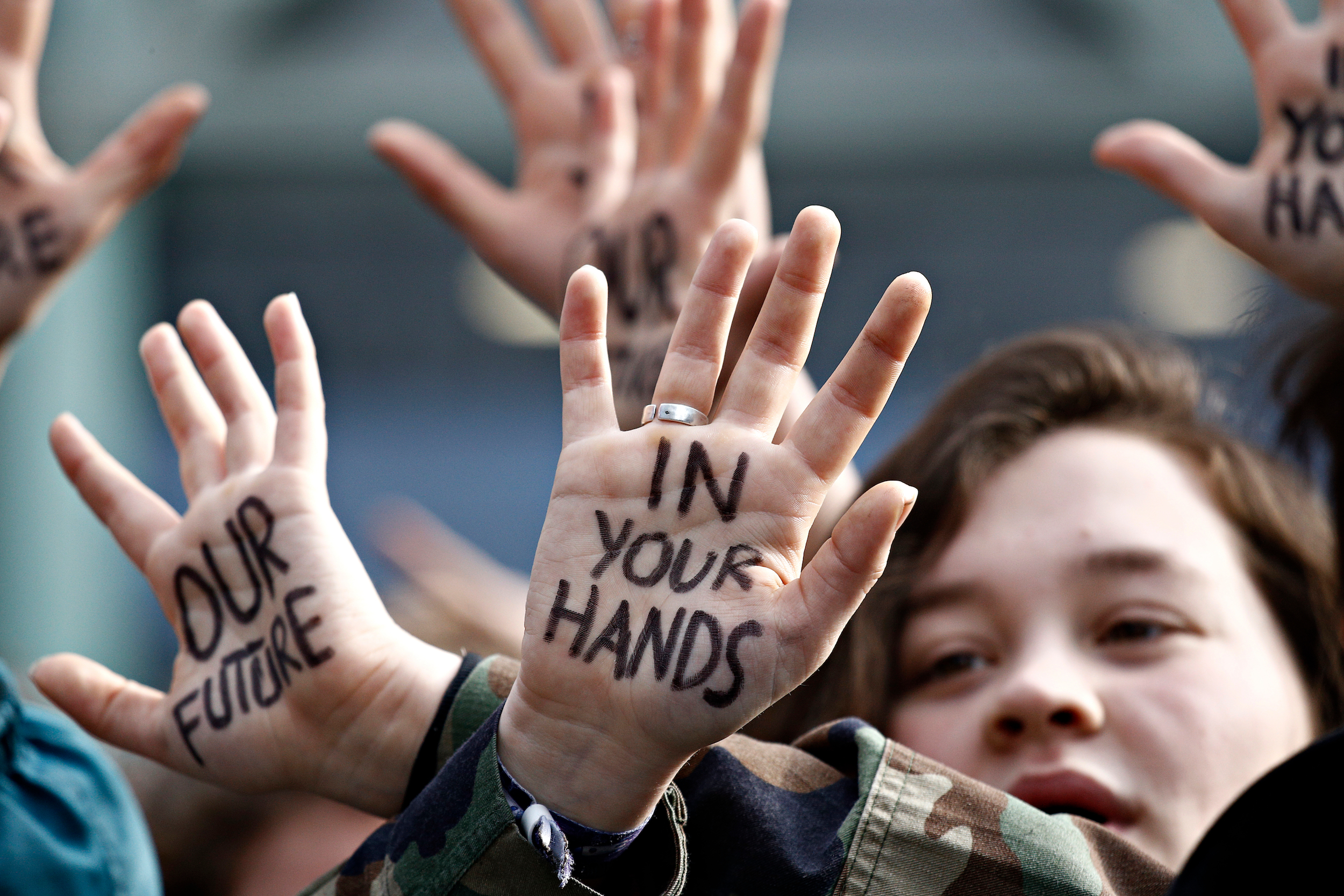 Students at a climate protest with "Our Future is in Your Hands" written on their hands