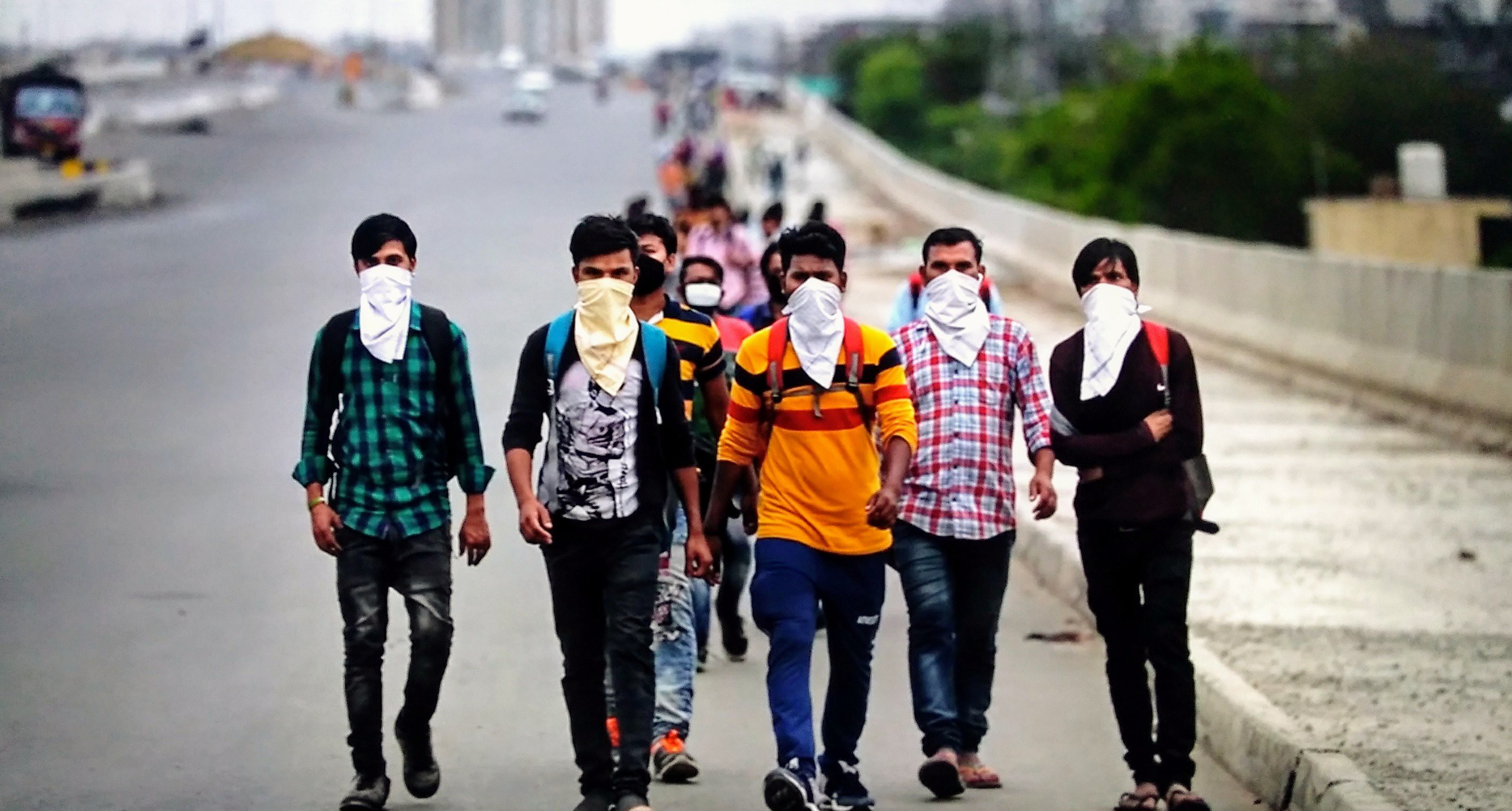 Men with face masks walking down a highway.