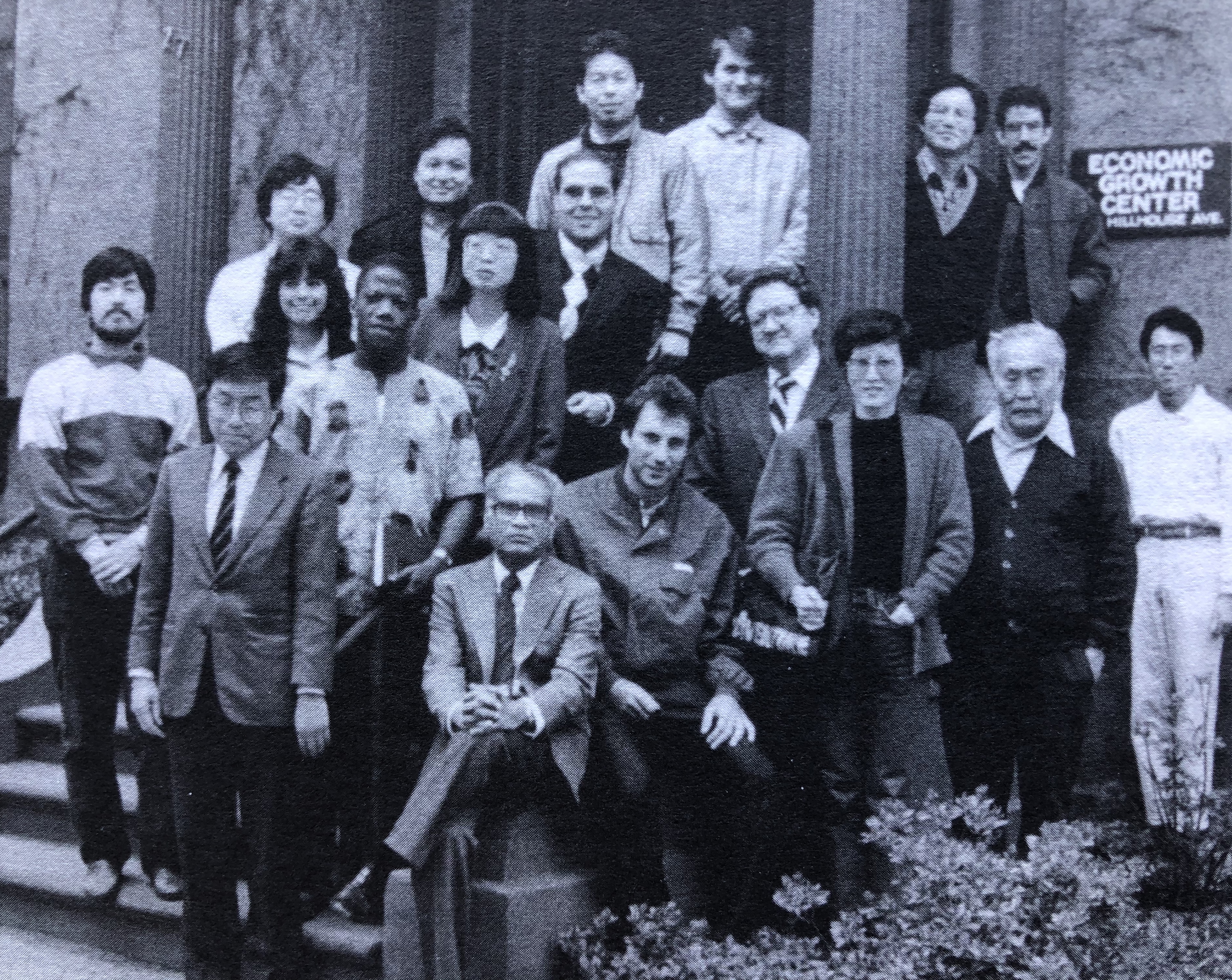 A group of 15 international students pose with professors on the steps of the EGC building
