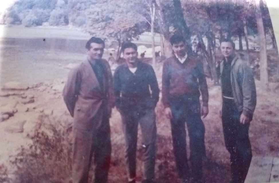 4 men standing outdoors near lake