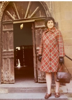 An image of Goldfarb in a red plaid coat standing at the top of some steps near a door