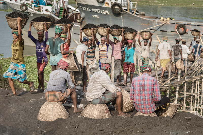 Men carry coal at a port in India.