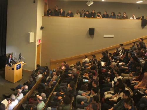 Penny Goldberg delivering a lecture to a packed auditorium.