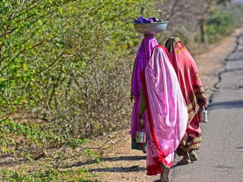 Indian women walking along a road, carrying items