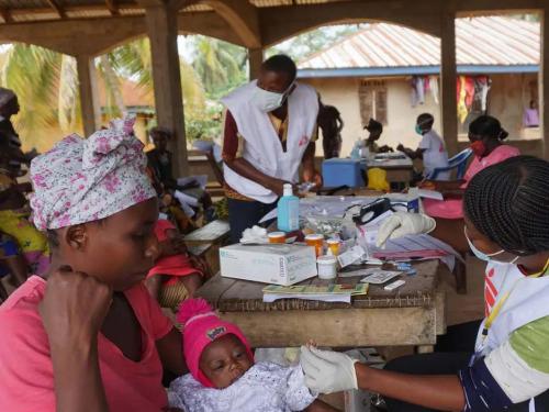 Photo: A Doctors Without Borders healthcare provider with a mother and her child at a mobile clinic in Sierra Leone in July 2020. Photo: Saidu Bah/AFP via Getty Images.
