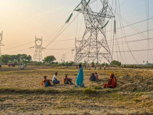 A group of rural Indian citizens watch construction of a high-voltage power line