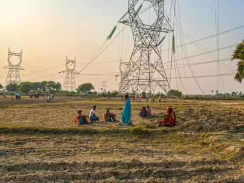 People in India in a field, surrounded by electrical towers and power cables