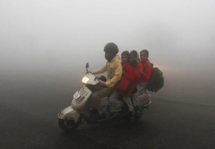 People riding on a motorbike in thick pollution.
