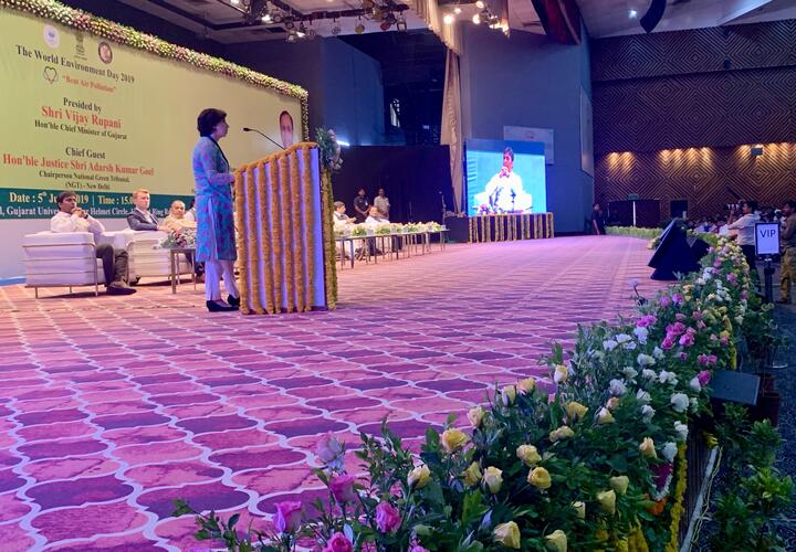 Rohini standing on stage speaking in front of full auditorium. 