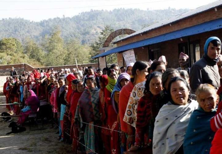 People wait in line outdoors for an election in Nepal.