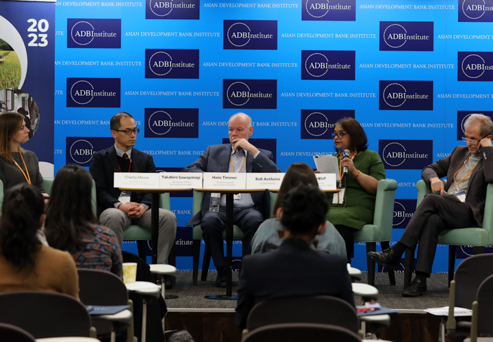 5 conference policy panelists sitting at roundtable on stage. 