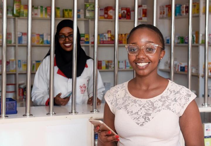 A young customer smiles after paying for goods and services through mobile money transfer in Kenya, Africa