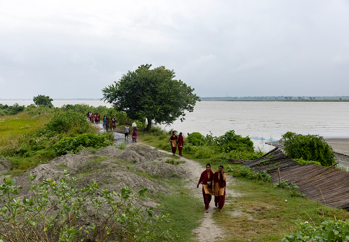 Women in Bihar walk down a road affected by flooding