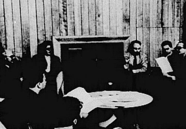 A black and white photo depicting scholars engaged in a discussion