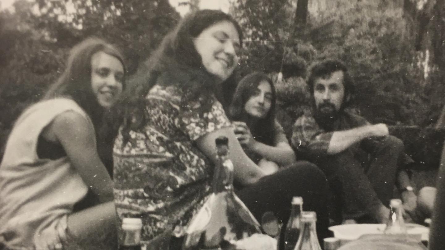 A group of young students in the 1960s – three women and a man – having a picnic.