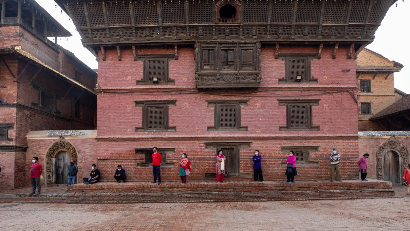People with masks waiting in line in front of Patan Durbar Square