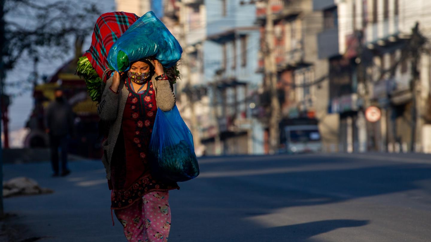 Migrant woman carrying her bags in Nepal, wearing a mask for Covid-19
