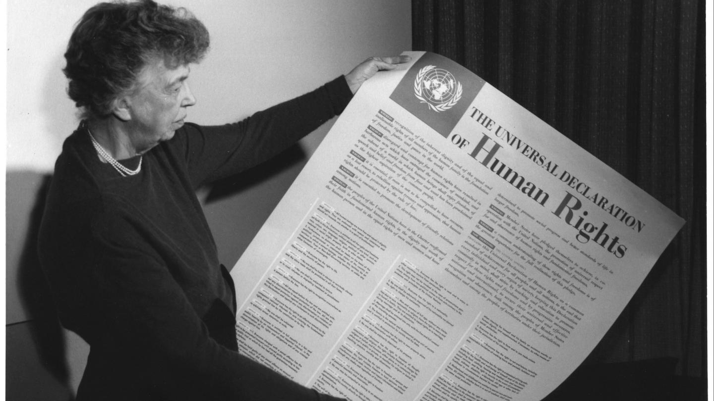 Eleanor Roosevelt holds a large printed copy of the Universal Declaration of Human Rights