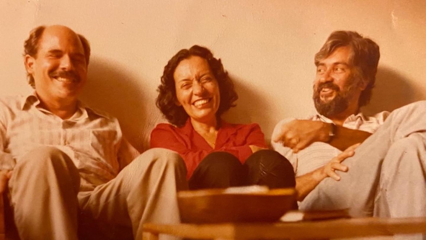 Carlos Diaz-Alejandro, Maria Conceição Tavares, and Edmar Bacha on a couch laughing,in Rio de Janeiro, Brazil in June 1980. Photo courtesy Edmar Bacha.