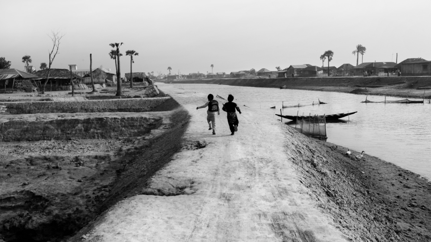 Two kids running on dirt road