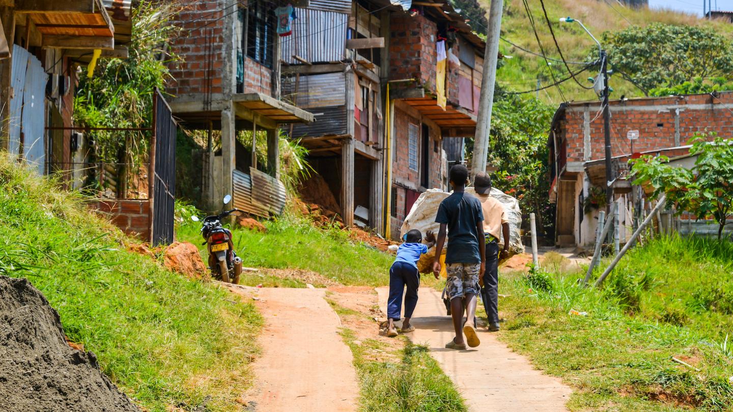 Three kids push their wheelbarrow of recyclable materials up the hill through their home, Comunidad 18 in Cali, Colombia.