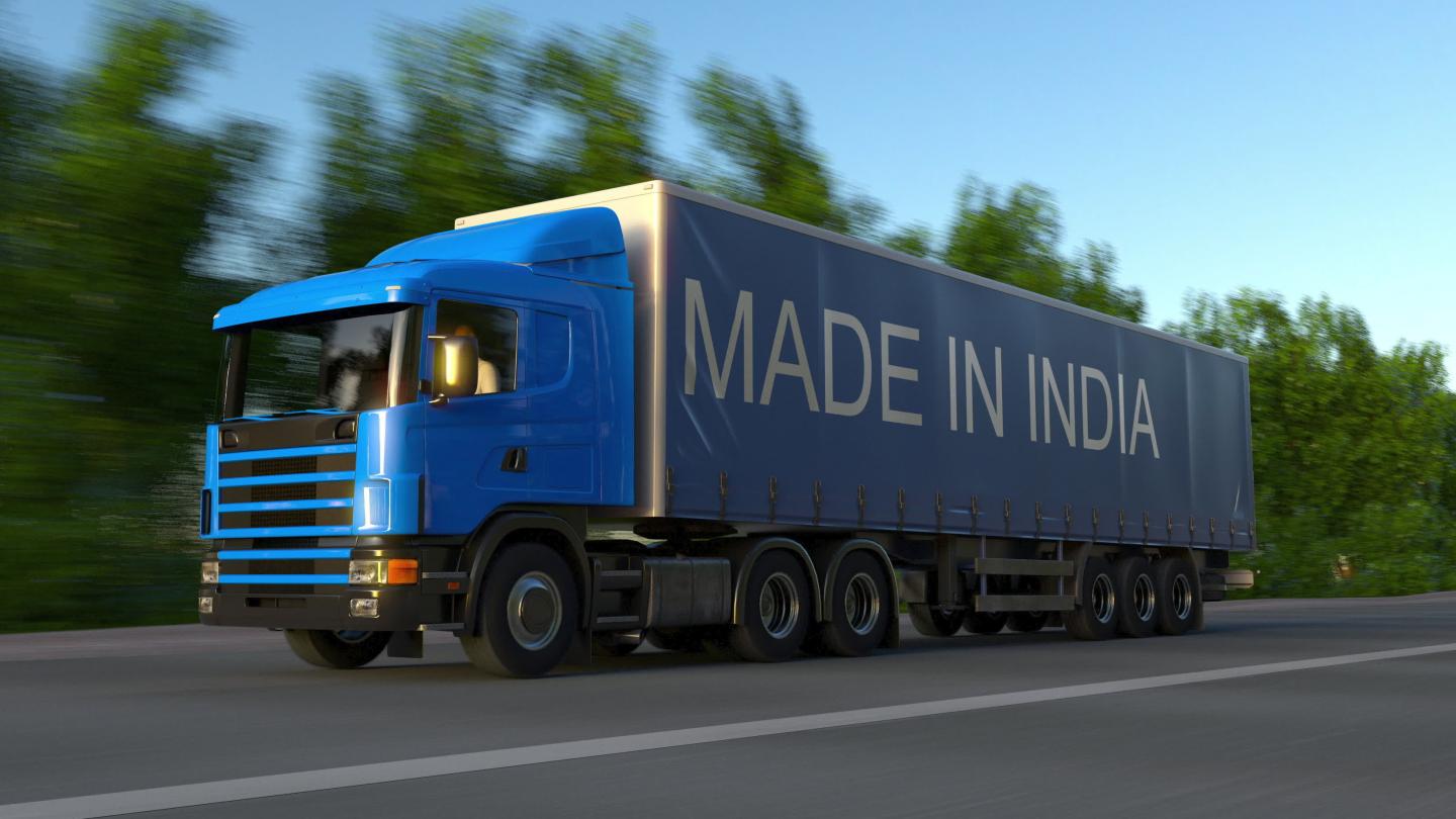 A truck printed with "Made in India" speeds down the highway